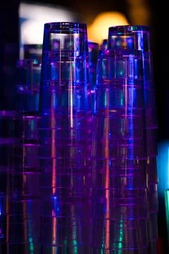 Stacked transparent plastic cups under neon lights. Stock Photos