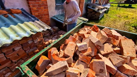Stacked Used Bricks With Worker Loading Materials in Sunny Outdoor Yard Stock Footage 314355201