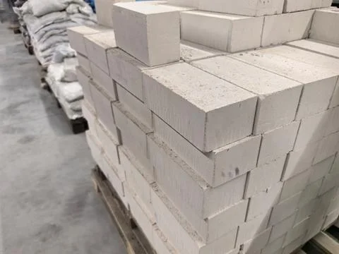Stacked white bricks ready for construction in a busy warehouse area Stockfoto's