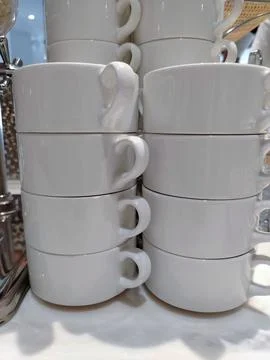 Stacked white ceramic coffee cups arranged neatly on a countertop, showcasi.. Stock Photos