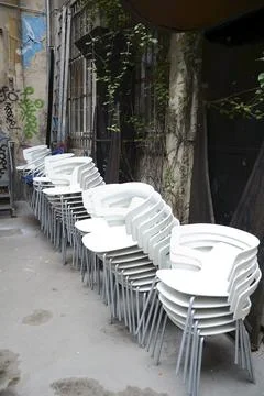 Stacked white chairs in a backyard in Berlin Stock Photos