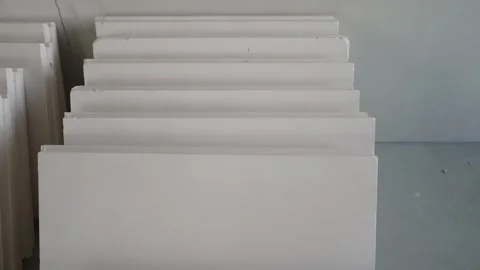 Stacked white drywall panels on concrete floor during renovation Stock Footage 334449268