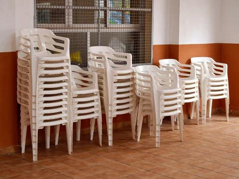 Stacked white plastic chairs preparing for public events Stock Photos