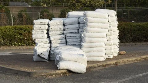 Stacked white plastic sacks filled with construction building materials aggre Fotos Stock