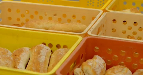 Stacked yellow and orange bakery crates filled with freshly baked rolls in bread Stock Footage 344589028