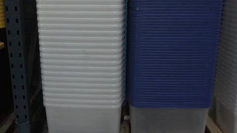 Stacked Yellow Plastic Storage Bin Lids on Wooden Pallets in Warehouse Видео 342391296