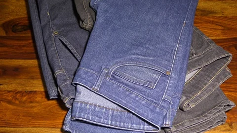 Stacking and removing jeans from table Stock Footage 128199325