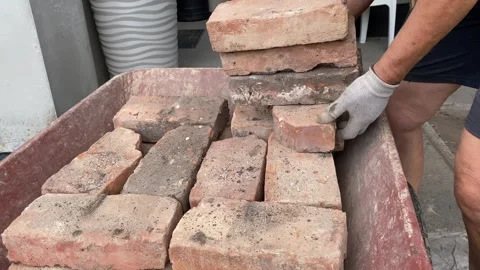 Stacking bricks from a red wheelbarrow Stock Footage 316539220
