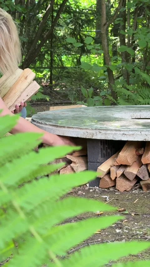 Stacking Firewood Under DIY Concrete Fire Pit Table Stock Footage 342002268