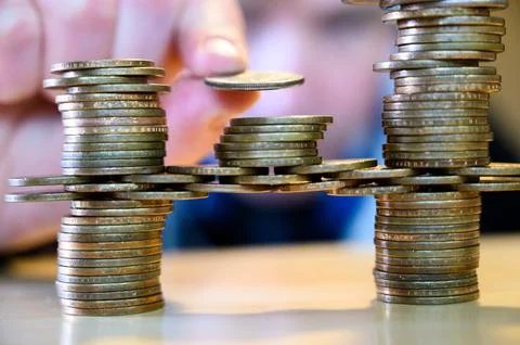 Stacking gold dollar coins into bridge using a cantilever Stock Photos