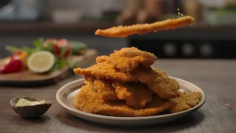 Stacking golden crispy chicken schnitzels for a mouthwatering feast 4K Stock Footage 328993788