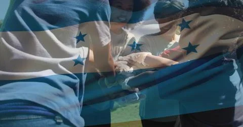 Stacking hands six people forming team huddle in park, wearing tees and gloves Stock Photos