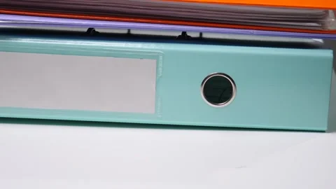 Stacking a light blue binder with a blank label and ring mechanism, plus other Stock Footage 342765721