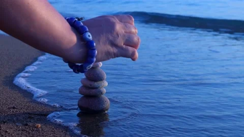 Stacking pebbles on the shore. 4K Stock Footage 195642302