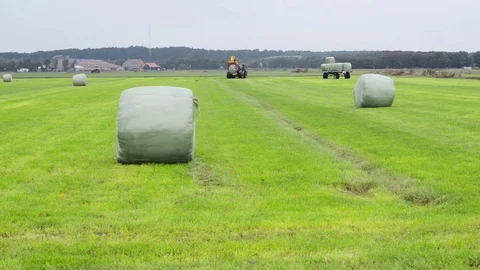 Stacking a plastic wrapped hay bale on a trailer Stock Footage