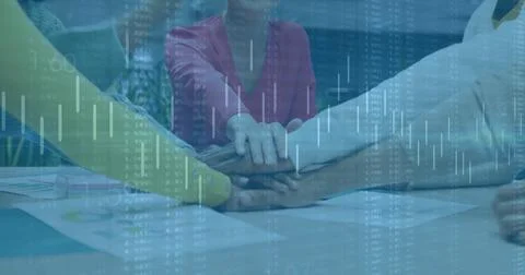 Stacking team hands over conference table in meeting room, with printed charts 스톡 사진