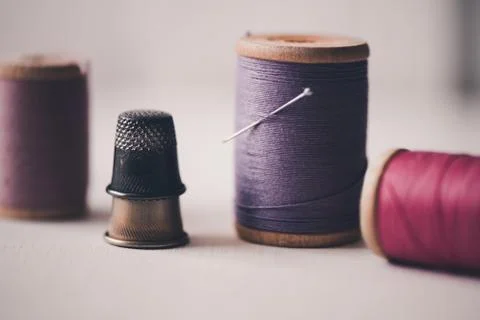 Stackof thimbles with spool of thread staying on table closeup. Handmade. Stock Photos
