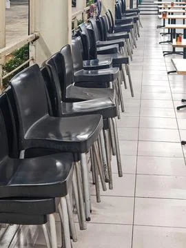 Stacks of Black Plastic Chairs in Empty Restaurant Dining Area Stock Photos