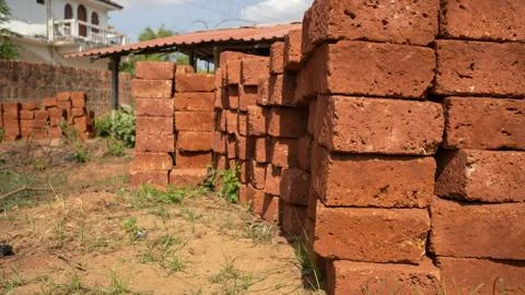 Stacks of bricks in yard. Shabby red bricks stacked on sandy ground with grass Stock Photos