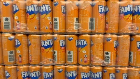 Stacks of bright orange soda cans wrapped in clear plastic on supermarket she Stock Footage 336273271