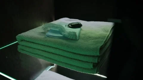 The stacks of clean bath towels on transparent shelves with green LED light Stock Footage 148963579