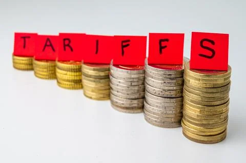 Stacks of coins and "tariffs" text. Increase in tariffs and costs. Stock Photos
