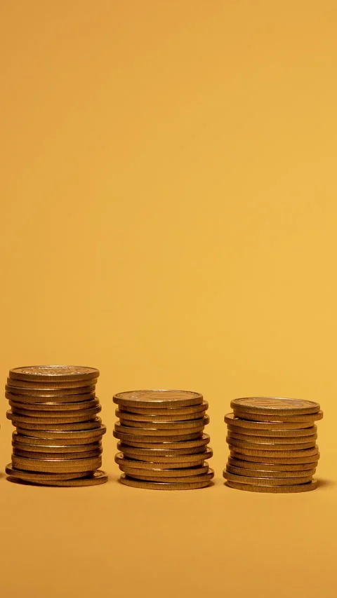 Stacks of coins arranged in increasing order against a warm yellow background Video stock 288319143