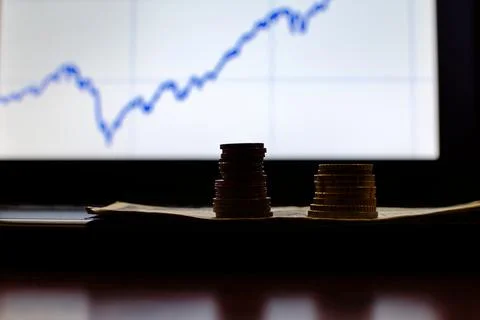 Stacks of coins on blurred computer screen Stock Photos