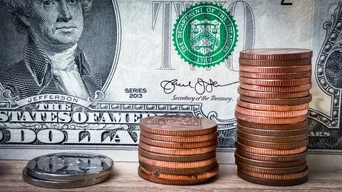 Stacks of coins in front of a two-dollar bill, concept of savings growth Stock Photos