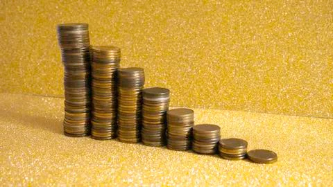 Stacks of coins with growth between stacking limits on gold background. Stock-Fotos