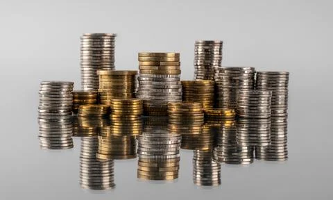 Stacks of coins in reflection on a grey background Stock Photos