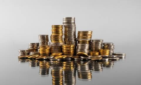 Stacks of coins in reflection on a grey background Stock Photos