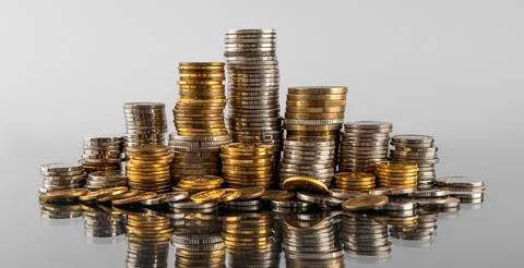 Stacks of coins in reflection on a grey background Stock Photos