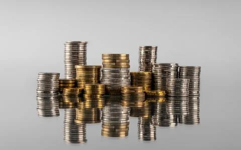 Stacks of coins in reflection on a grey background Stock Photos