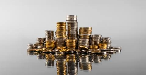 Stacks of coins in reflection on a grey background Stock Photos