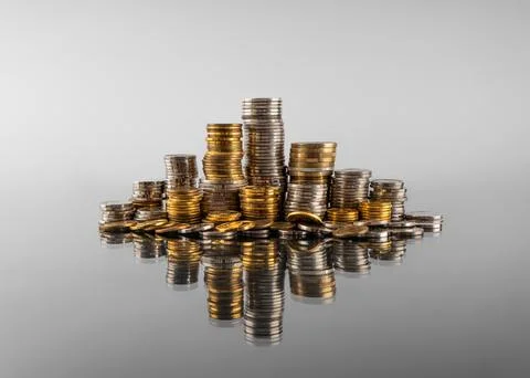 Stacks of coins in reflection on a grey background Stock Photos