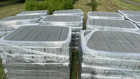 Stacks of concrete paving blocks wrapped in plastic on wooden pallets  Видео 340997785