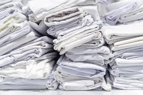 Stacks of folded white fabric on a smooth table organized piles clean texti.. 스톡 사진