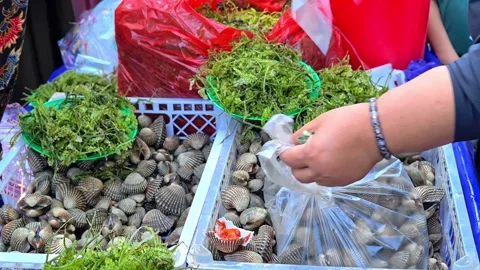 Stacks of fresh crabs and clams on display at a traditional fish market. Видео 338338623