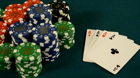 Stacks of gambling chips and four of a kind cards on aces on green casino table Stock Footage 221420282