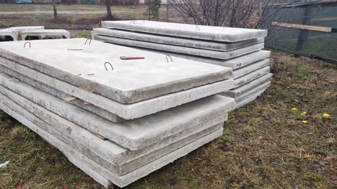 Stacks of heavy grey concrete slabs for road construction, featuring metal hooks Stock Footage 344094790
