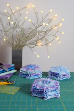 Stacks of hexagonal patchwork blocks, quilting accessories, table lamp on a.. Stock Photos