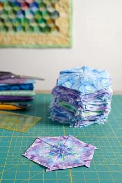 Stacks of hexagonal patchwork blocks, quilting accessories against the back.. Stock-Fotos