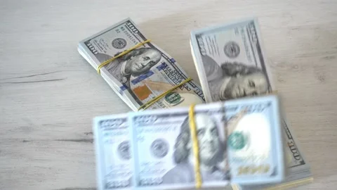Stacks of hundred dollar bills fall on the table in 4K. Stock Footage 233028770