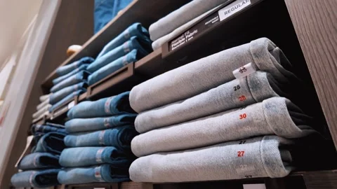 Stacks of jeans and pants displayed on shelves in a clothing store Vídeo Stock 334759102