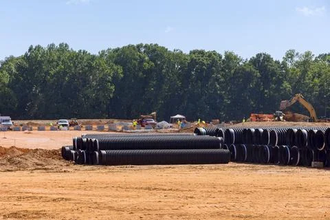 Stacks of large black plastic sewerage pipes are waiting to be installed on Stock Photos