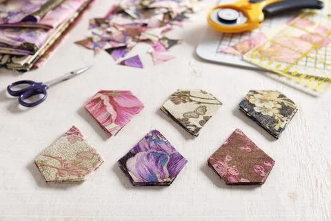 Stacks of multi-colored pentagonal pieces of fabric, scissors, ruler Stock-Fotos