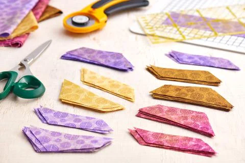 Stacks of multi-colored pieces of fabric, scissors, rotary cutter, cutting ma Stock-Fotos
