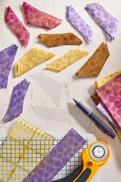 Stacks of multi-colored pieces of fabric, ruler, cutting mat, rotary cutter,  Stock Photos