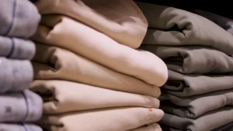 Stacks of neatly folded items in a closet. Pants stacked by color in a store Stock Footage 314982514
